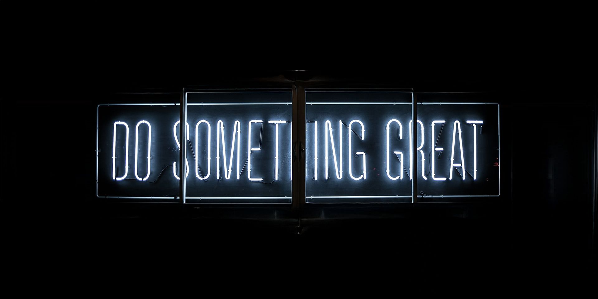 Neona gaismas zīme ar uzrakstu “DO SOMETHING GREAT”.